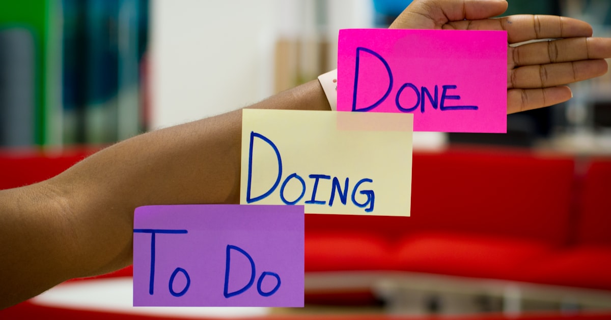 Sticky notes reading To Do, Doing and Done held against a desk.